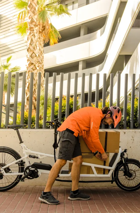 Un coursier charge un colis dans la caisse de son vélo cargo