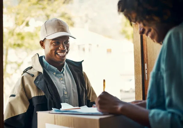 Livreur qui effectue une livraison le jour même d'un carton à une personne à domicile