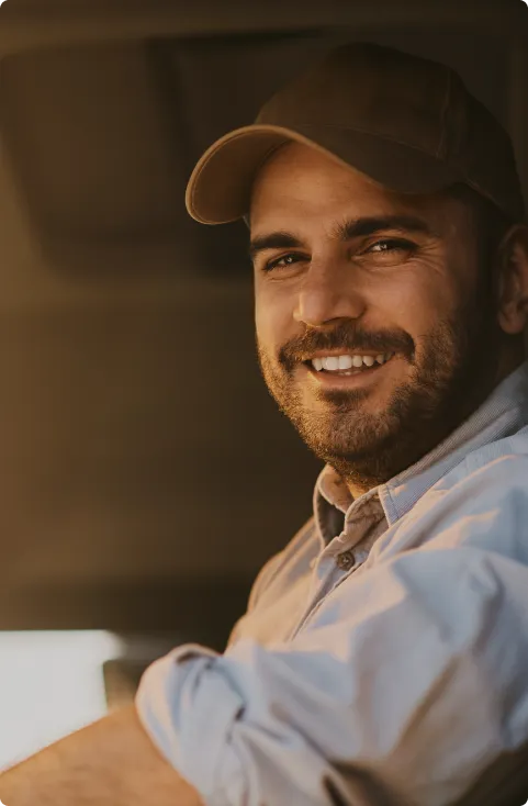 Un chauffeur souriant au volant de son camion, le coude à la portière
