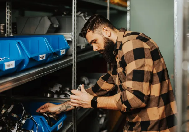 Magasinier prélevant une pièce dans des bacs de stockage étiquetés
