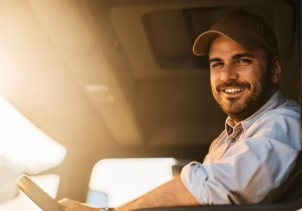 Chauffeur-livreur souriant au volant de son utilitaire