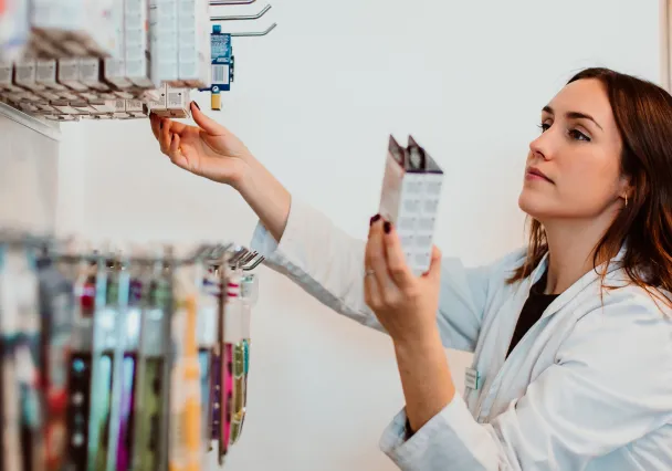 Pharmacienne prélevant une boîte de médicaments dans un rayonnage automatisé