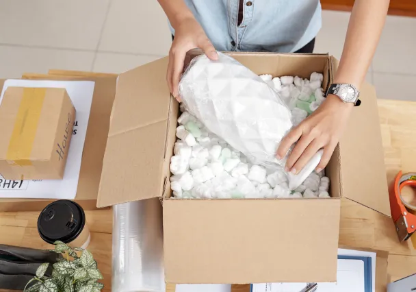 personne qui prépare un envoi de colis fragile dans un carton fragile