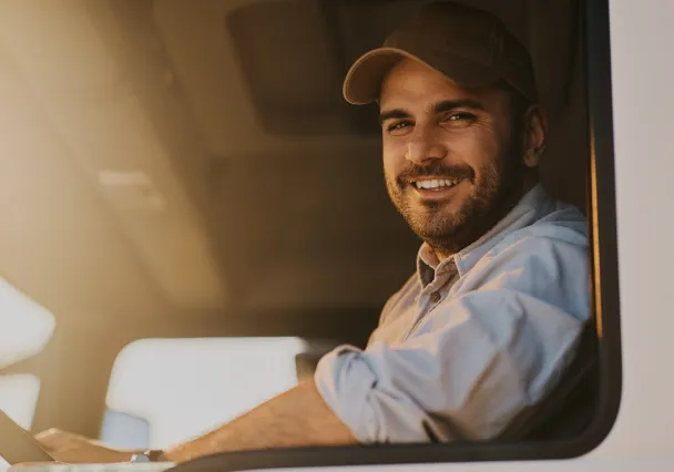 Chauffeur-livreur souriant au volant de son utilitaire
