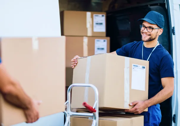livreur portant un carton devant sa camionnette ouverte
