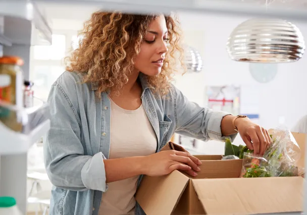 Cliente déballant un carton de légumes frais dans sa cuisine