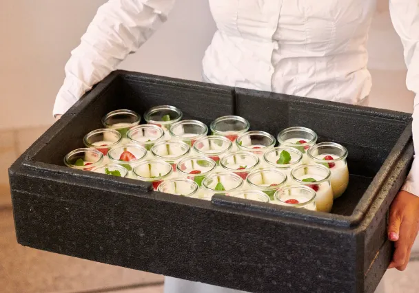 Personne portant un bac isotherme rempli de verrines de dessert