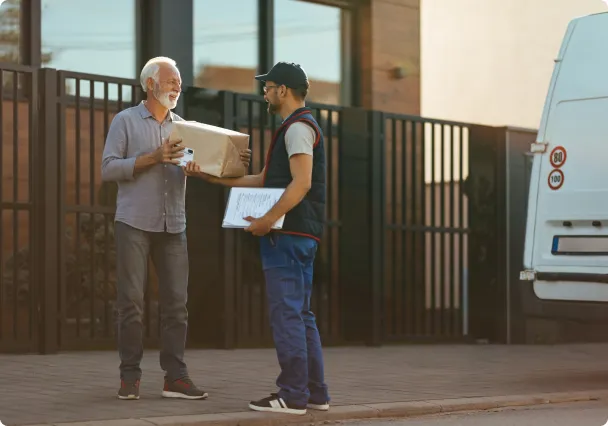 Un livreur remet un colis à un client devant chez lui