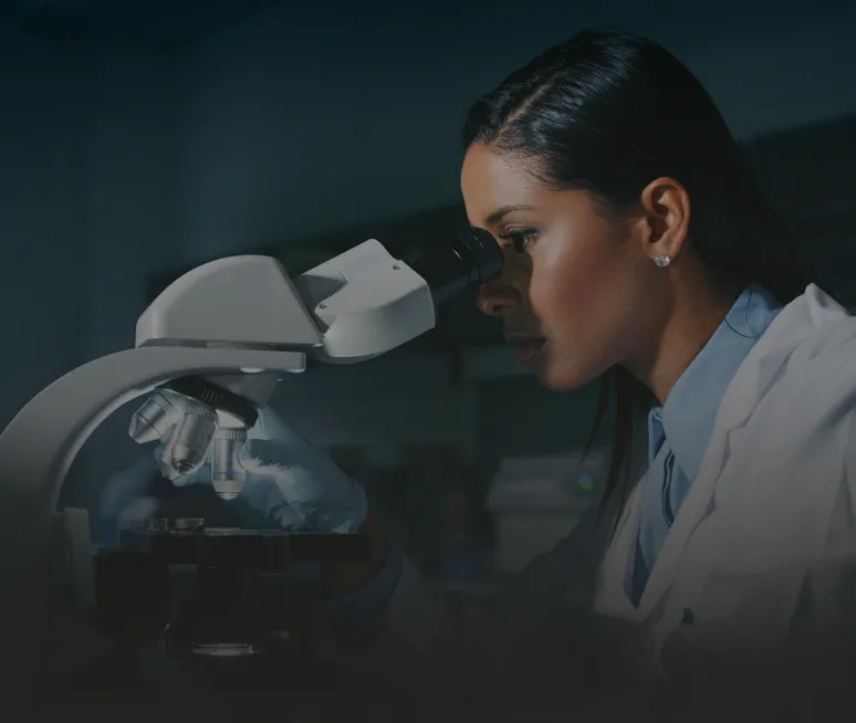 Laborantine en blouse blanche au microscope