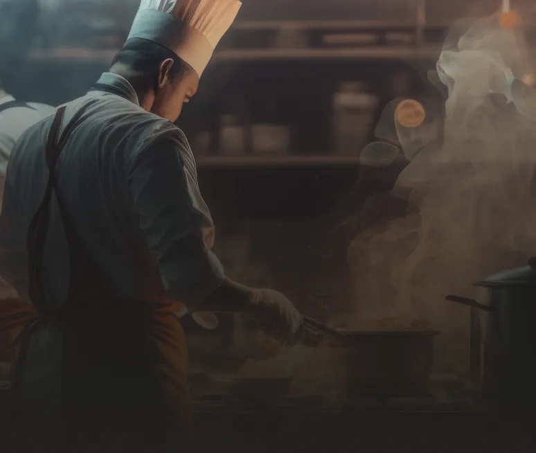 Chef en toque dressant un plat aux fourneaux