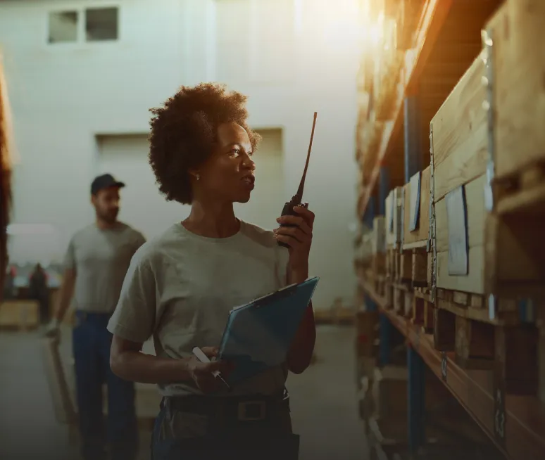 Responsable d’entrepôt coordonnant les préparations à la radio dans les allées de stockage