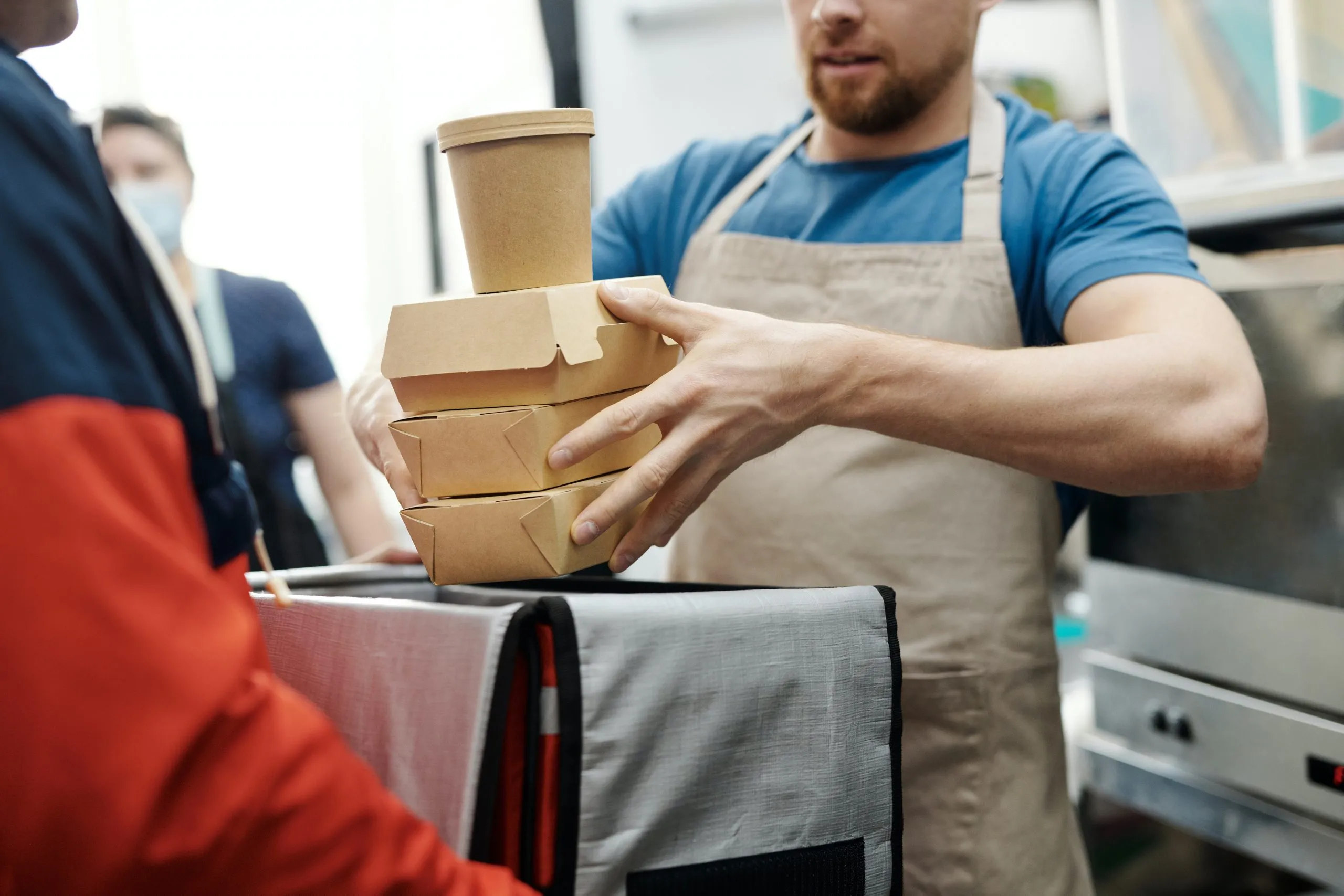 Cuisinier qui met des plats dans un sac réfrigéré pour une livraison