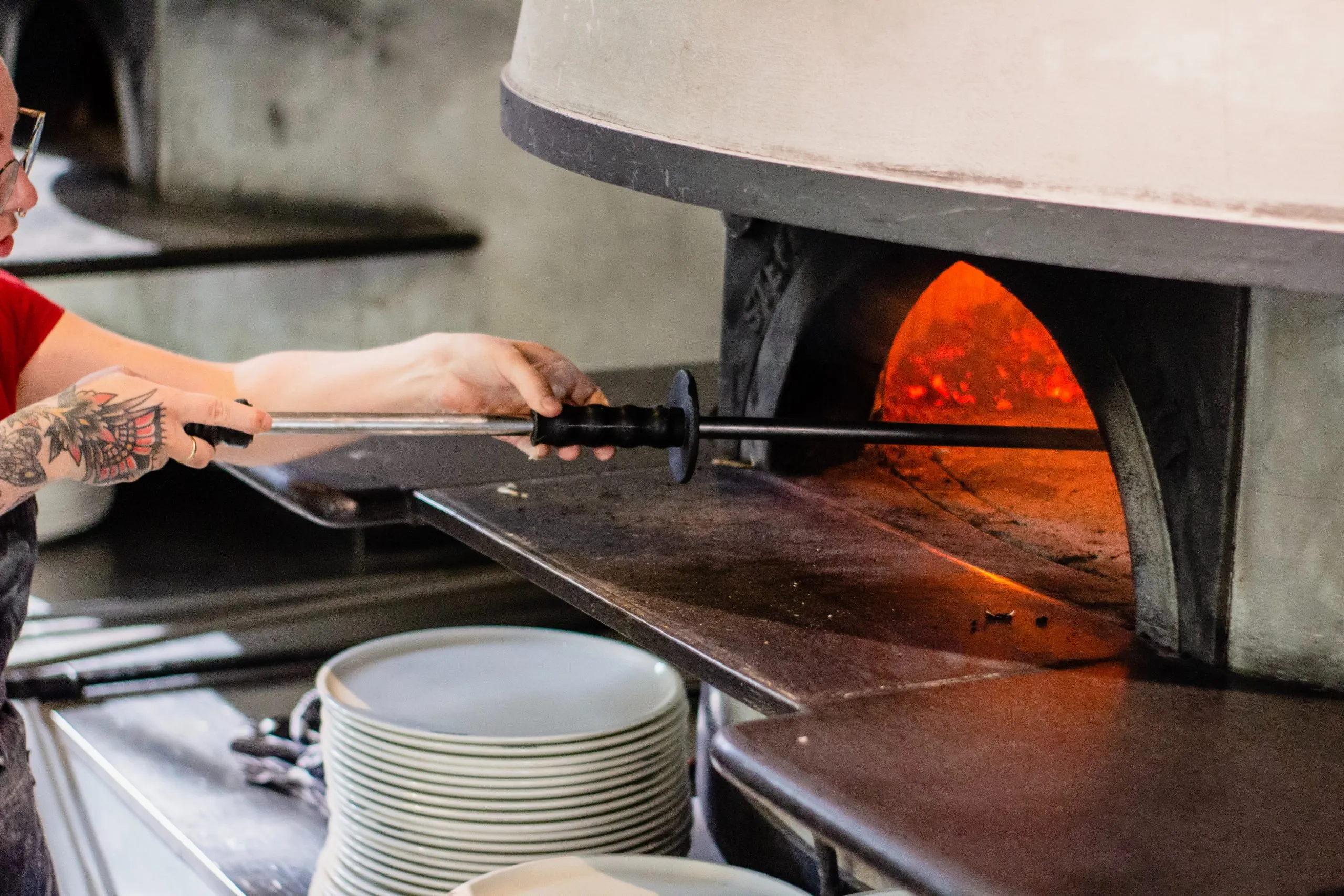 un pizzaolo mettant une pizza dans son four à pizza