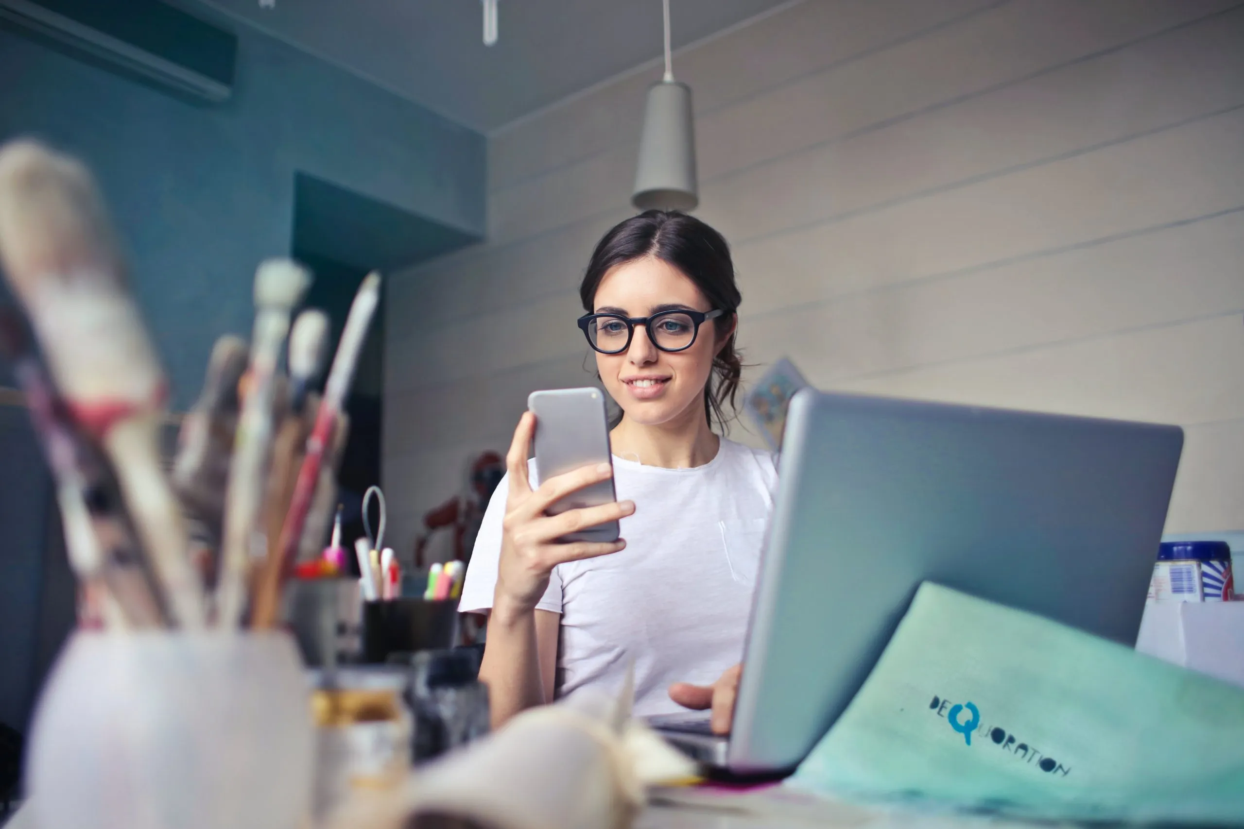 fille qui tient un smartphone devant son ordinateur