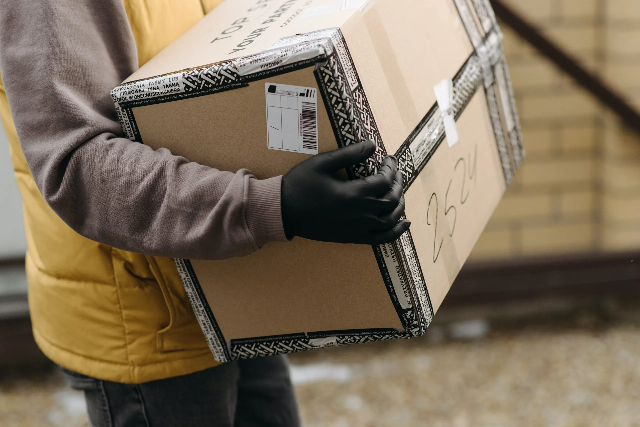 livreur qui porte un colis en carton