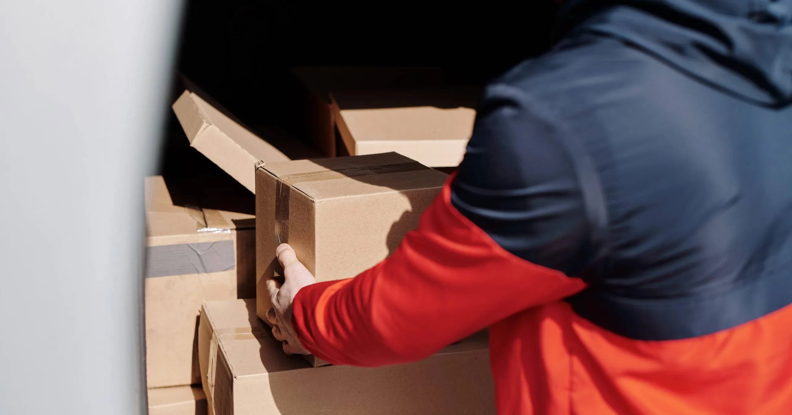 livreur prenant des caisses en carton de sa camionnette