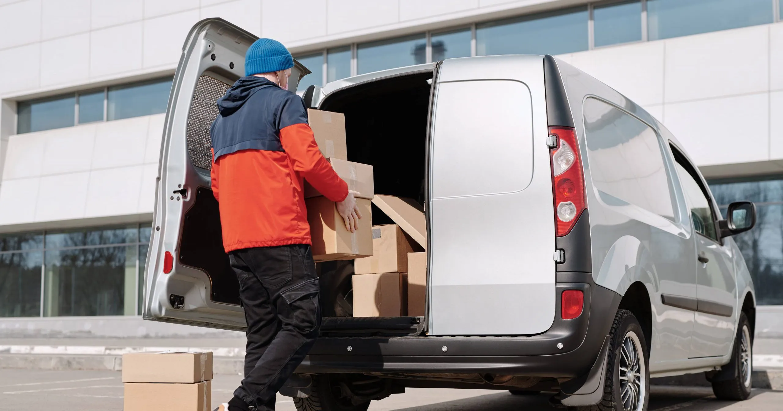 livreur portant des caisses en carton dans sa camionnette