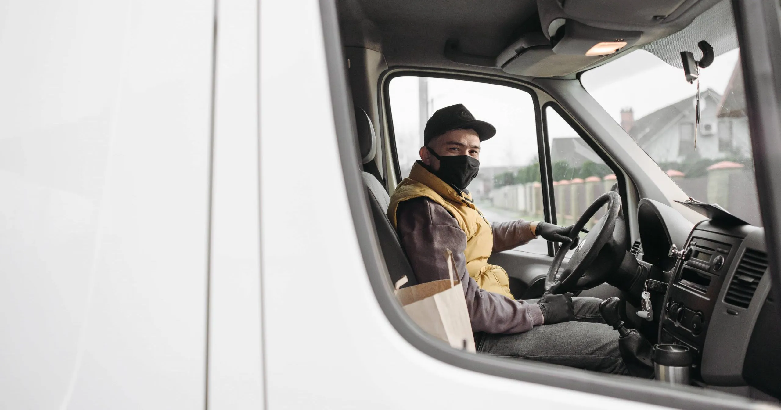 livreur de colis en masque dans son camion