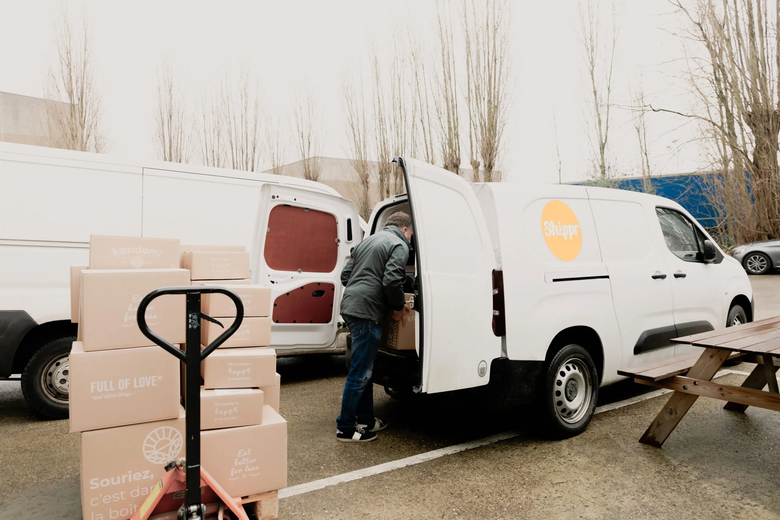 Livreur Shippr mettant des caisses en carton dans sa camionnette blanche