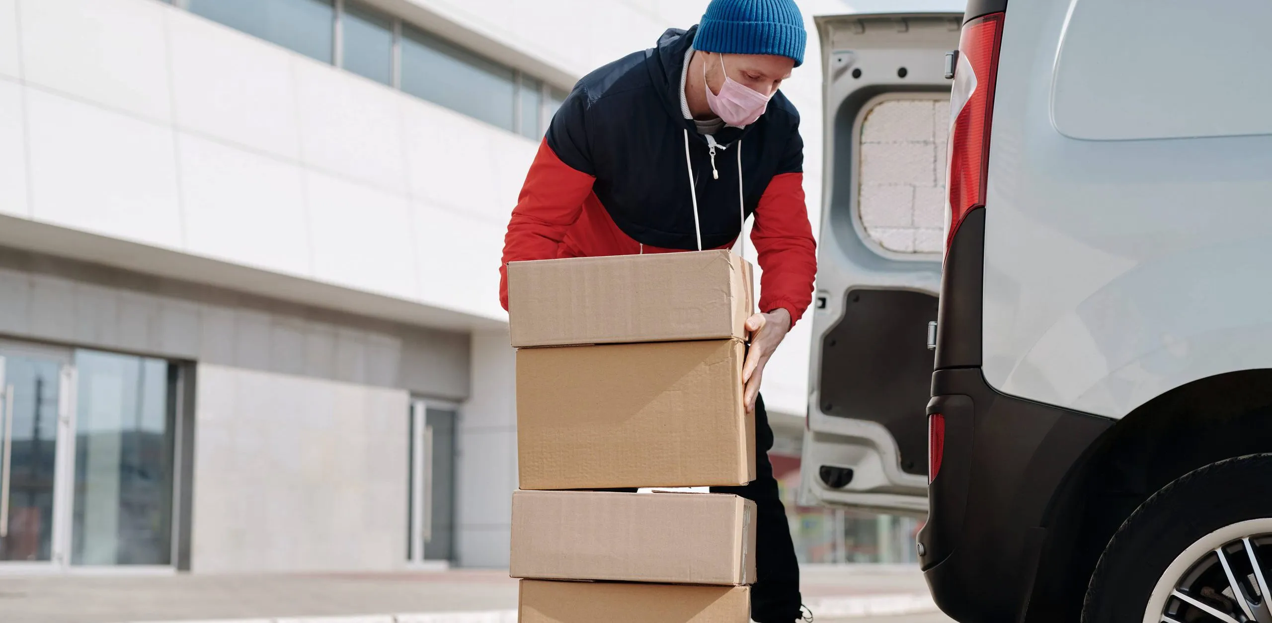 Livreur indépendant plaçant des caisses en carton dans sa camionnette