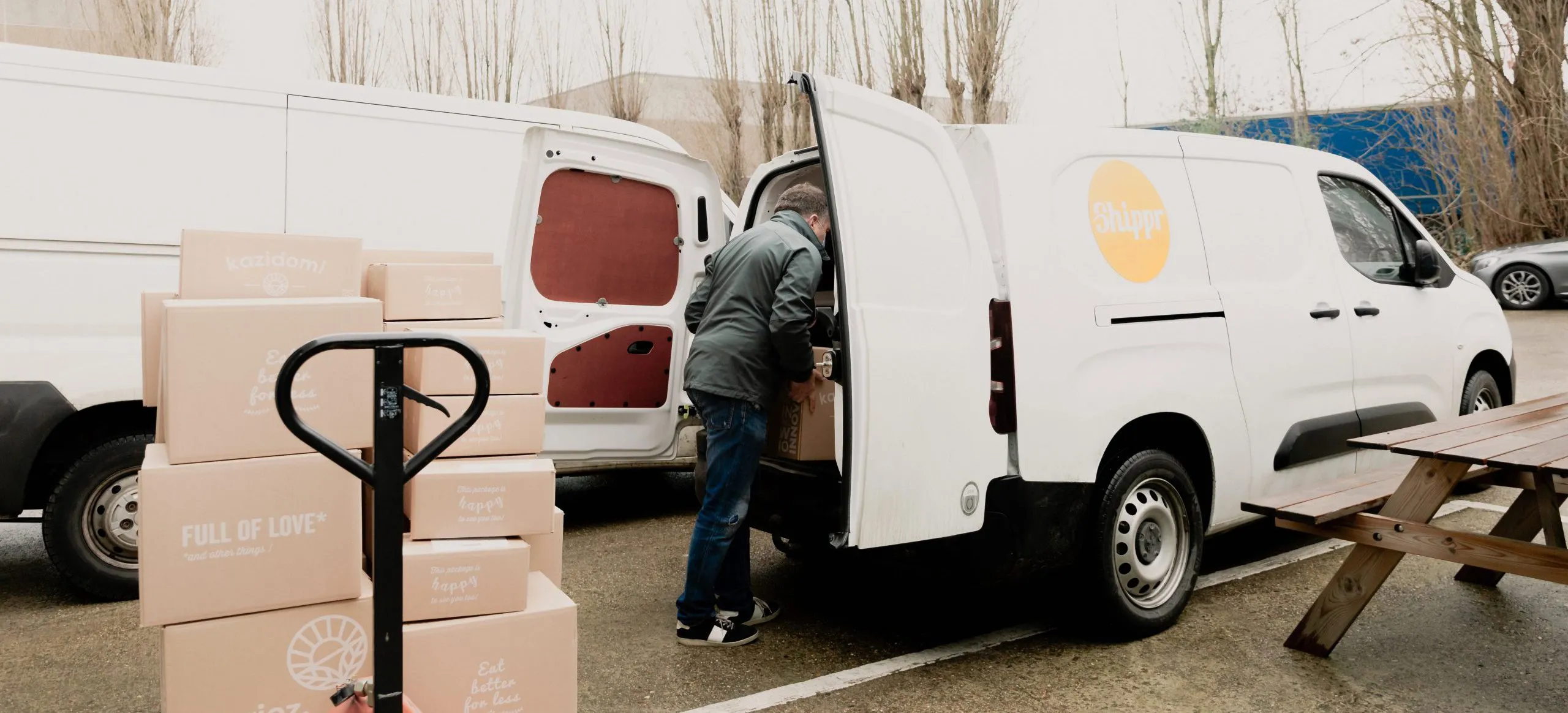 livreur posant des caisses en carton kazidomi dans sa camionnette blanche avec logo shippr