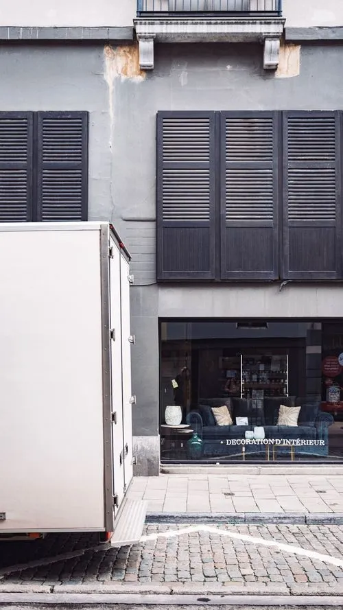 Camion de livraison blanc devant une vitrine d'un magasin de décoration intérieur