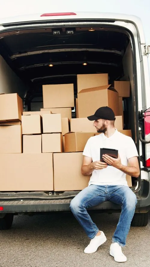 Livreur devant sa camionnette ouverte qui fait des tournées de livraison pour l'environnement